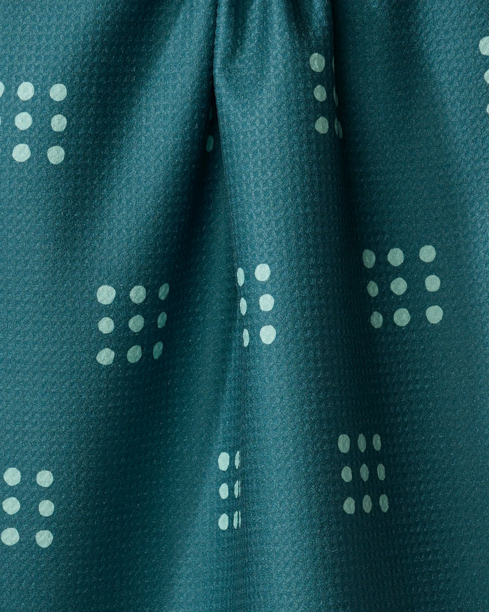 The Elizabeth Edwards Seafoam Grid tea towel features dark teal fabric with a subtle texture and clusters of light teal dots in square grids. Softly gathered at the center, this quick-drying towel adds style to any kitchen.