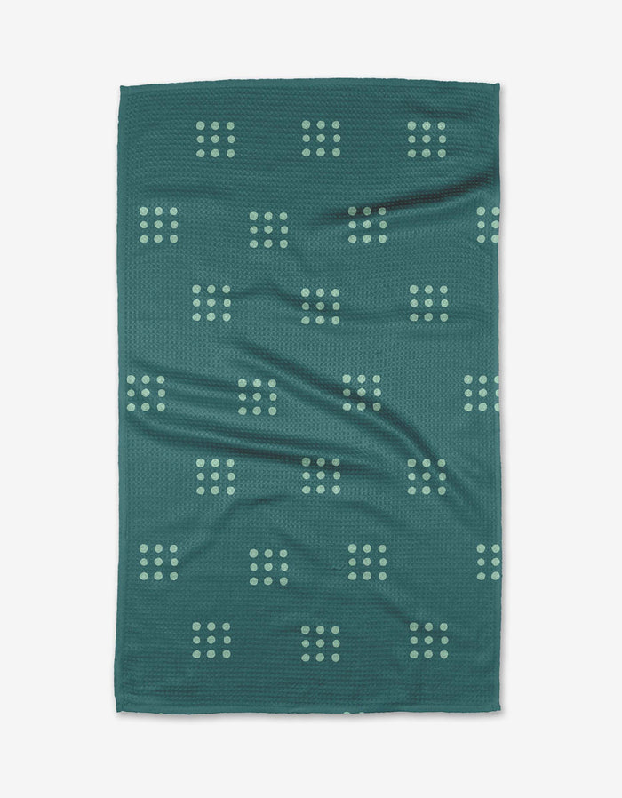 The Elizabeth Edwards Seafoam Grid towel features a dark teal rectangular design with light green grid dots, crafted from ultra-absorbent Geoweave fabric. Slight surface wrinkles are visible against the white background.