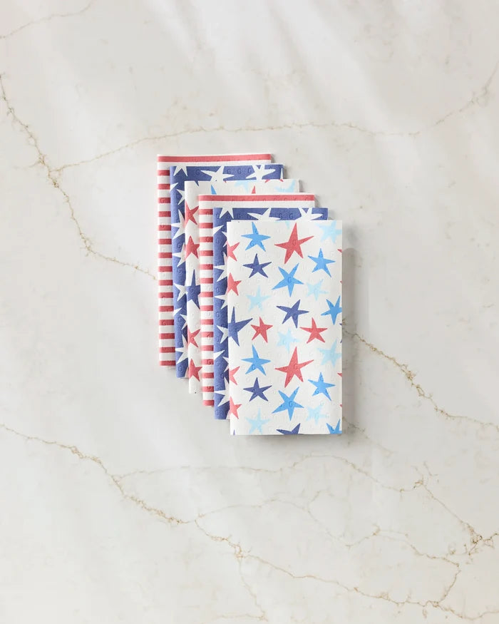 Four folded Mindfulnice Seeing Stars reusable paper towels are stacked on a light marble surface, featuring red, white, and blue star and stripe patterns for a patriotic Americana look. These eco-friendly napkins are perfect for your kitchen.