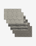 The Self Love placemats by Danelys Sidron include six black and white mats made from eco-friendly recycled materials, featuring two cursive script, two striped, and two checkerboard patterns.