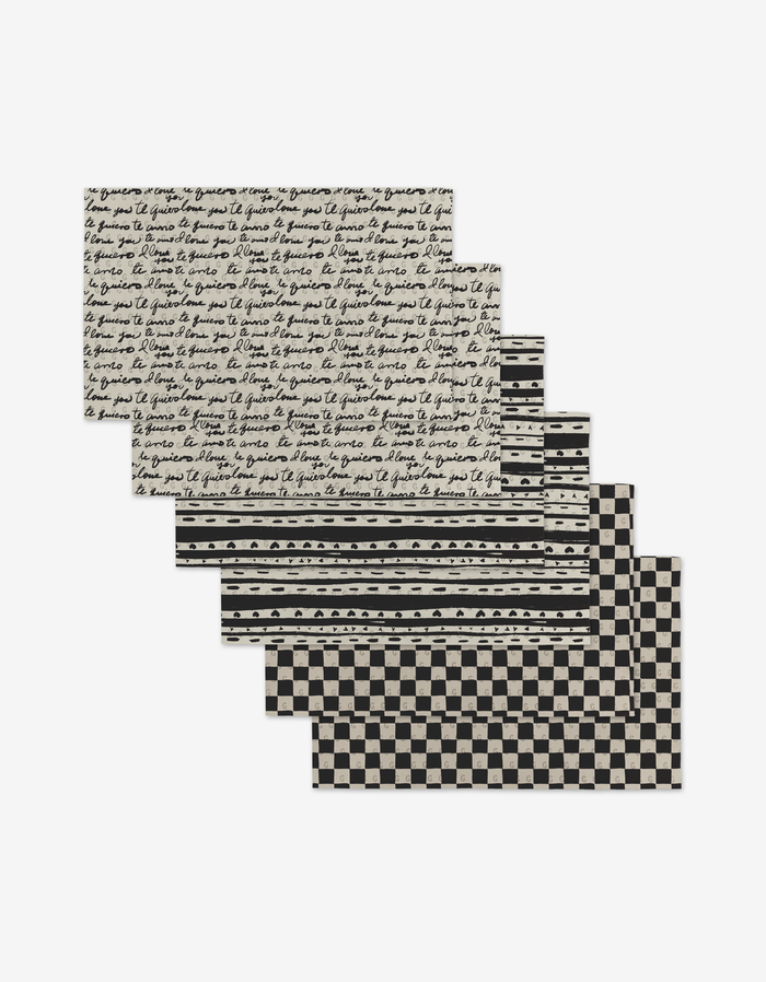 The Self Love placemats by Danelys Sidron include six black and white mats made from eco-friendly recycled materials, featuring two cursive script, two striped, and two checkerboard patterns.