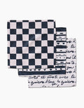 Three folded Self Love dish towels by Danelys Sidron are stacked: the top shows a black and white checkerboard, the middle has stripes with hearts, and the bottom features black cursive script—each made from durable Geoweave fabric.