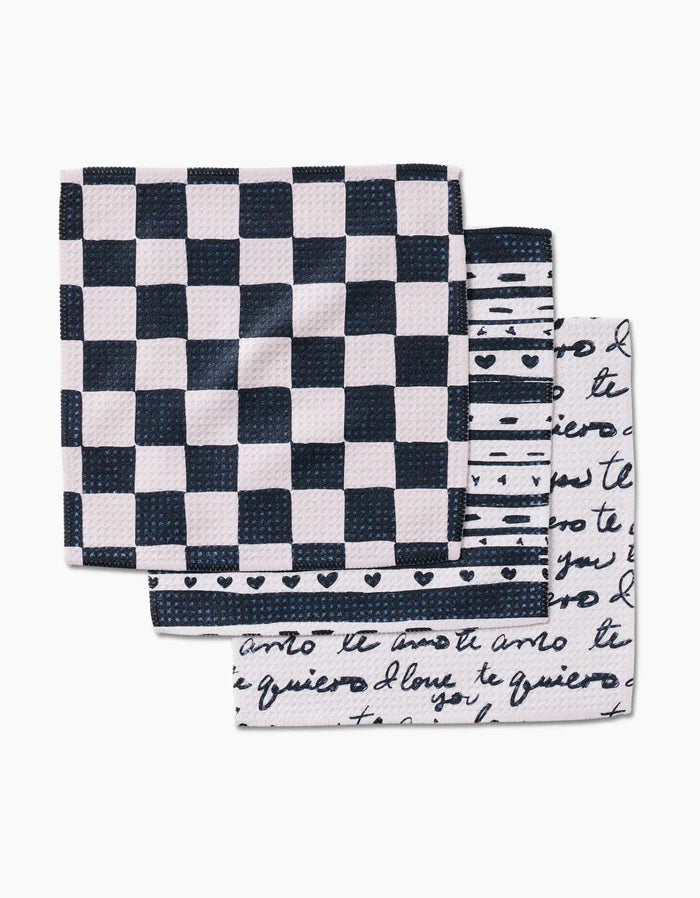 Three folded Self Love dish towels by Danelys Sidron are stacked: the top shows a black and white checkerboard, the middle has stripes with hearts, and the bottom features black cursive script—each made from durable Geoweave fabric.