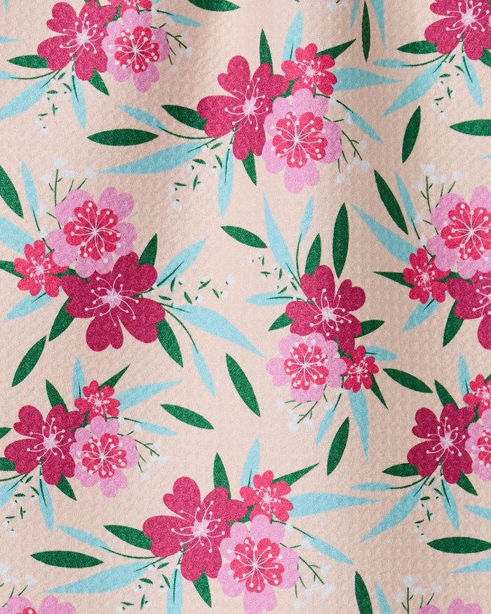 The GEOMETRY Sending Love bar towel features clusters of pink and magenta flowers with green and teal leaves on beige. Made from recycled materials, it offers a slightly textured, ultra-absorbent surface.