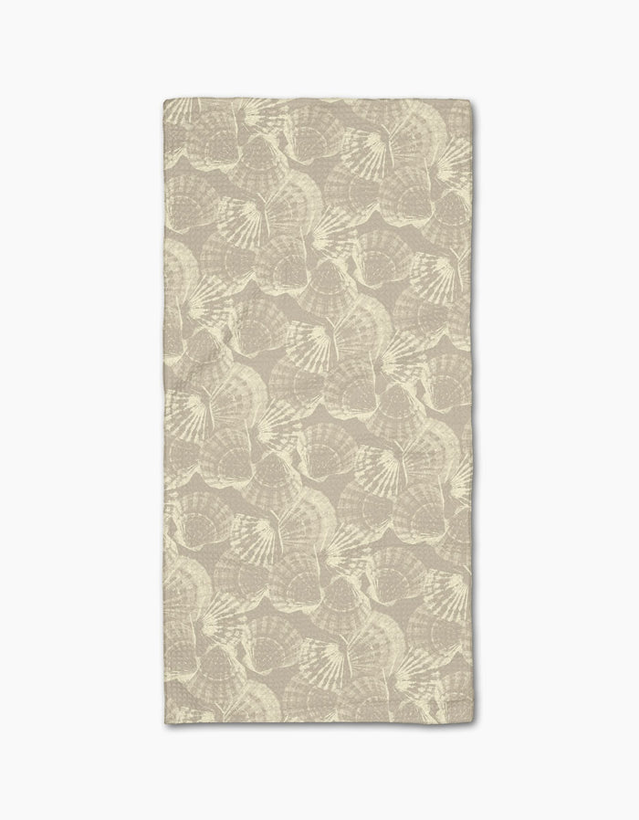 Shell Whisper by Geometry is a rectangular beige cloth napkin, made from post-consumer recycled materials, featuring a subtle, repeating light ginkgo leaf pattern and displayed flat on a white background.