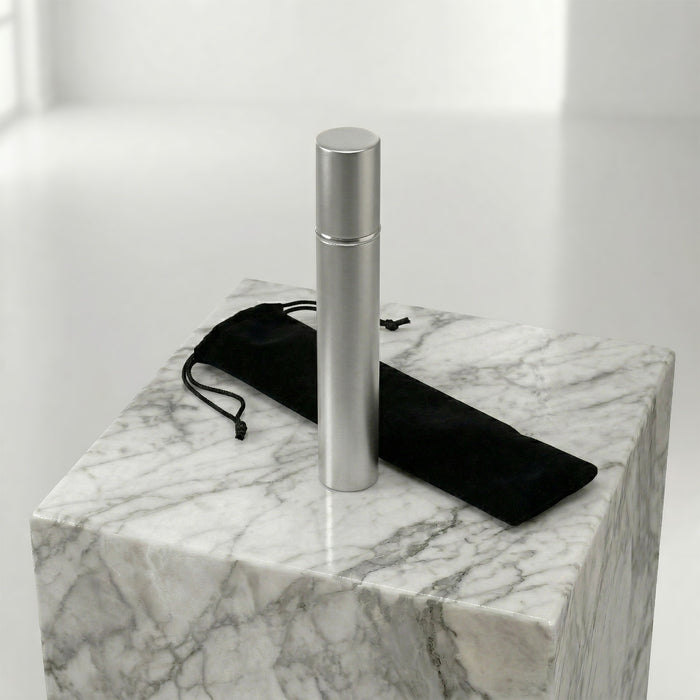 Silver scattering tube on a marble surface with a black drawstring pouch.