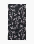The Toboggan Avenue Sketchbook Dust bar towel is black, rectangular, and made from Geoweave fabric. It features a white minimalist botanical pattern with delicate, abstract flower and leaf outlines across the surface.