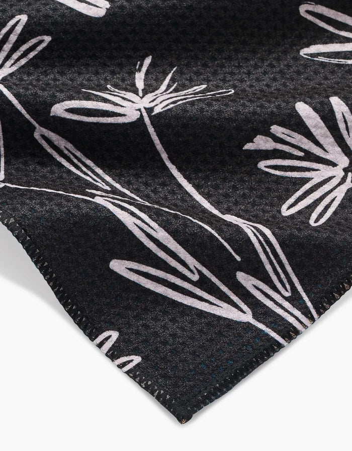 Close-up of Toboggan Avenues Sketchbook Dust: a dark Geoweave bar towel with a subtle textured pattern, white abstract floral line drawings, and neatly stitched edges.