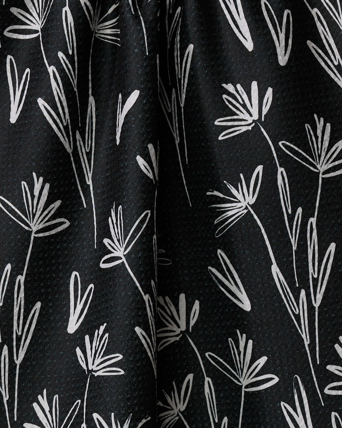 The Sketchbook Dust tea towel by Toboggan Avenue features black fabric with subtle dots and a white abstract floral line-art pattern—perfect for adding a chic, modern touch to your kitchen and quick-drying convenience.