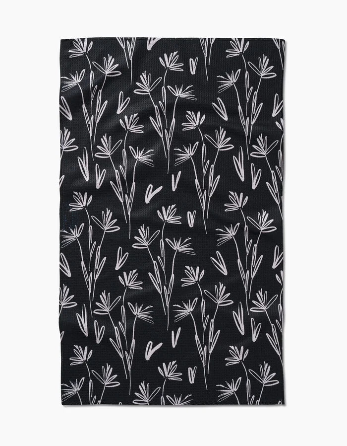 The Sketchbook Dust tea towel by Toboggan Avenue is black with a white hand-drawn floral and heart pattern in a scattered, repeating design. Made from durable, elegant Geoweave™ fabric.