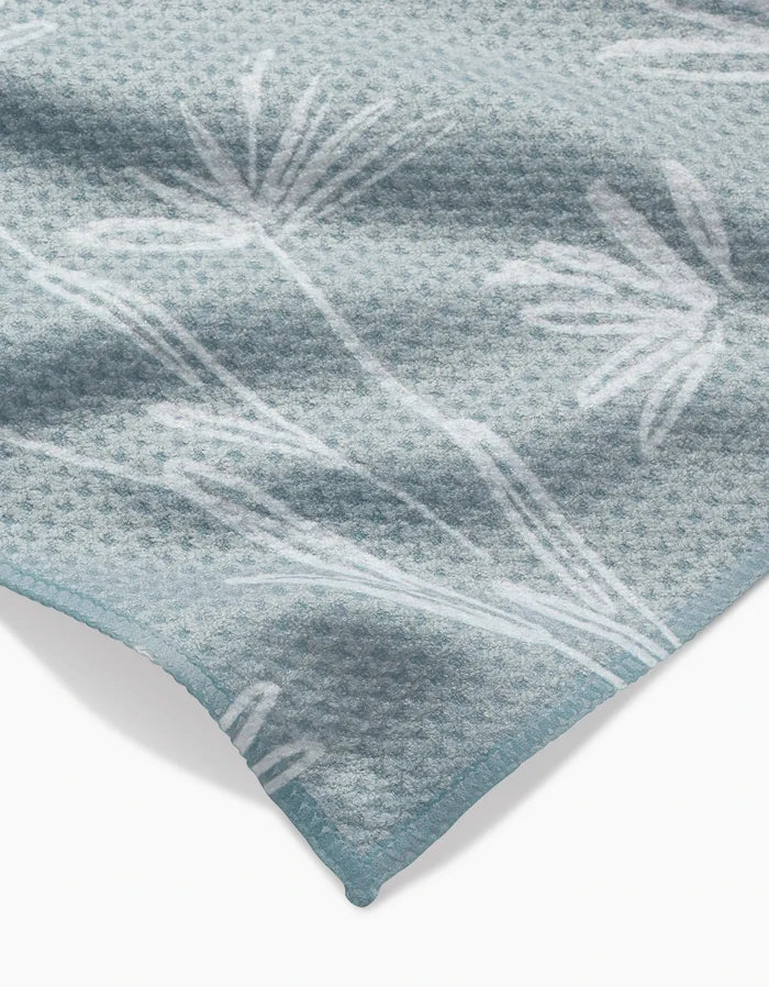 A close-up of Toboggan Avenues Sketchbook Floral Bar Towel in light blue Geoweave fabric, featuring a subtle white botanical pattern and a neatly finished corner.