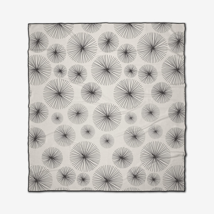 The GEOMETRY Sky Party is a rectangular white micro-loop beach blanket with evenly spaced black radial starburst patterns of varying sizes and a thin black border.