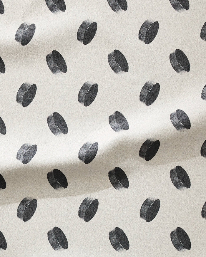 The Geometry Slapshot is a cream-colored, ultra-absorbent fitness towel made from recycled materials, featuring black 3D polka dots and a softly textured surface with gentle folds for style and function.