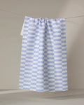 The Buy Guide’s Small Stripe - Navy tea towel, featuring absorbent white fabric with evenly spaced navy stripes, hangs from a string against a neutral background.