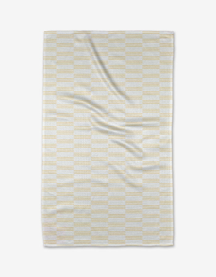 The Buy Guide’s Small Stripe - Yellow Tea Towel, shown flat on a white background, features a light yellow and gray stripe pattern. Made from soft Geoweave™ fabric, it displays gentle folds and slight creases for a cozy appearance.