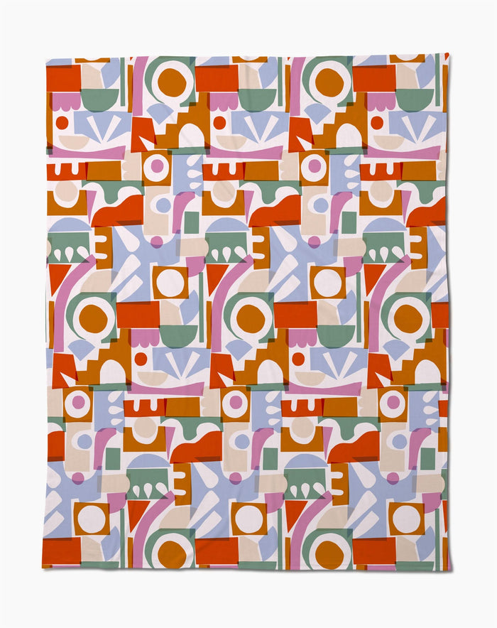 The Soft Cutouts Garden Butter Blanket by Claire Iglesias features colorful geometric shapes—circles, rectangles, and arches in red, orange, green, pink, lilac, and white on a light background—crafted from eco-friendly recycled materials.