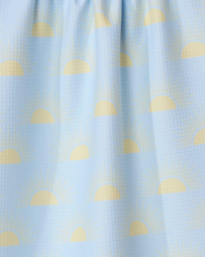The GEOMETRY Soft Summer Sun tea towel features a light blue textured design with yellow half sun and sunbeam patterns, made from recycled materials.