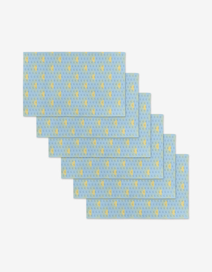 Six Soft Summer Sun rectangular blue placemats by GEOMETRY, featuring small yellow duck and blue circle patterns, made from eco-friendly post-consumer recycled materials, are fanned out and overlapping on a white background.