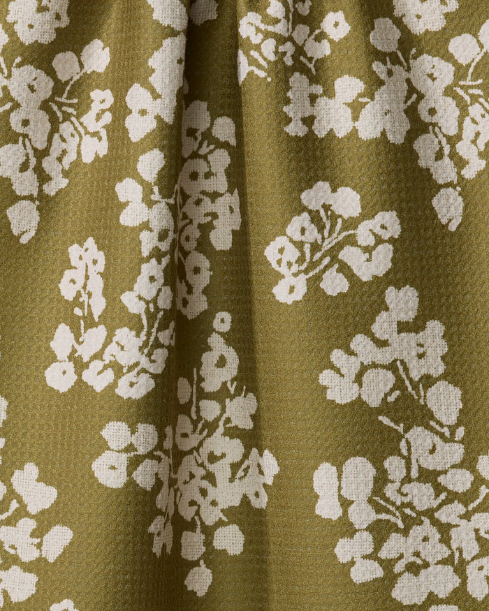 The Geometry Sonnet Olive towel features ultra-absorbent olive green fabric with a textured surface and clustered white floral patterns, creating gentle shadows and soft variations in the material.