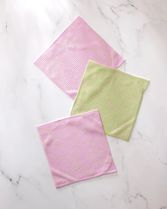 Three square washcloths from GEOMETRY’s Speckle Green Pink set—two pink with multicolored dots, one light green with pink, yellow, and white dots—made from recycled materials and crafted for super absorbency.