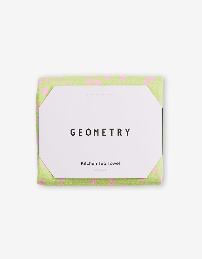 The GEOMETRY Speckle Green kitchen tea towel, made from Geoweave fabric with pink polka dots and measuring 18 x 30 inches, comes folded in white packaging labeled GEOMETRY.