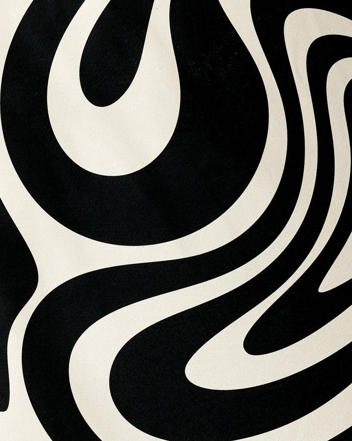 The GEOMETRY Spiral yoga towel features a bold black and white swirling abstract pattern, creating an optical illusion effect on its textured recycled surface.