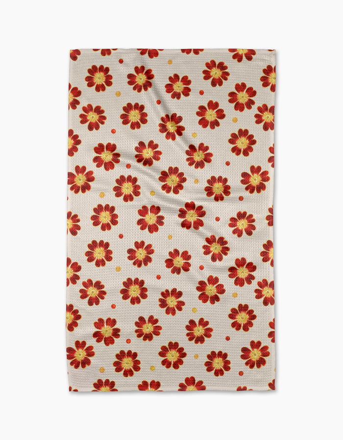 The Linda Fox Spotty Floral tea towel is beige and rectangular, with a repeating red and yellow flower pattern and small red dots. Made from quick-drying recycled materials, it’s shown laid flat with subtle wrinkles.