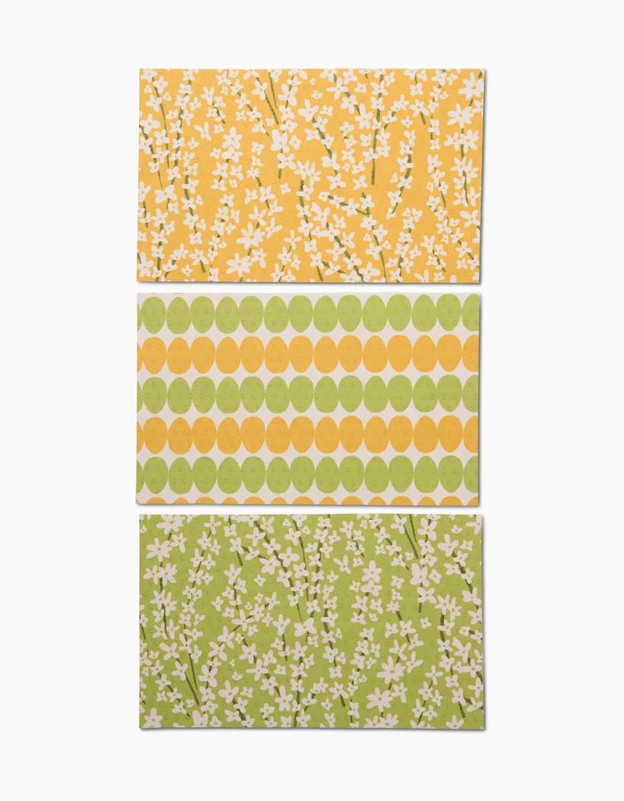 Kayla Ann’s Spring Bounty set features three rectangular sheets: one yellow with white florals, one with green and yellow circle rows, and one eco-inspired sheet—green with white floral patterns.