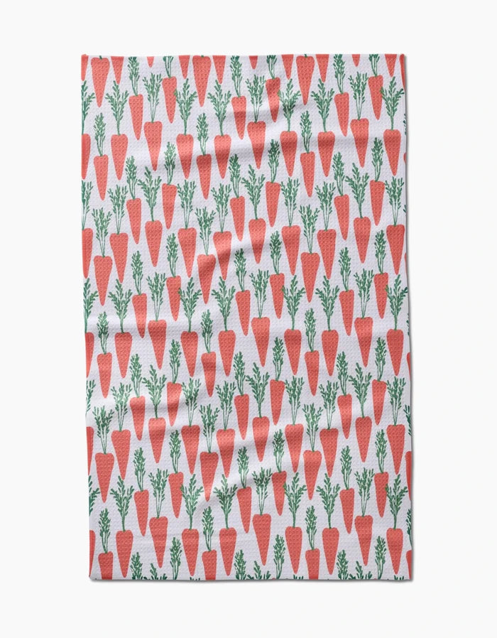 The Spring Carrot Hill tea towel by Hufton Studio displays orange carrots with green tops in neat rows across a white background.