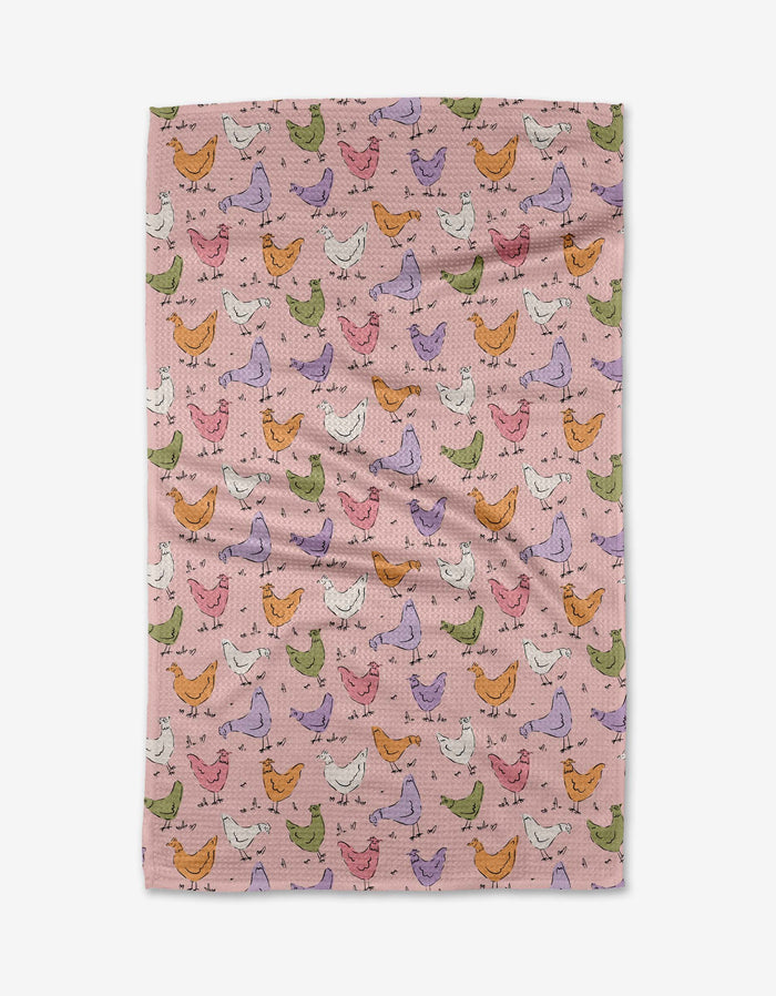 The Kayla Ann Spring Chickens tea towel features a pink background with colorful chickens in green, orange, purple, and white. Ultra-absorbent and slightly wrinkled for charm, it adds a playful touch to your kitchen.