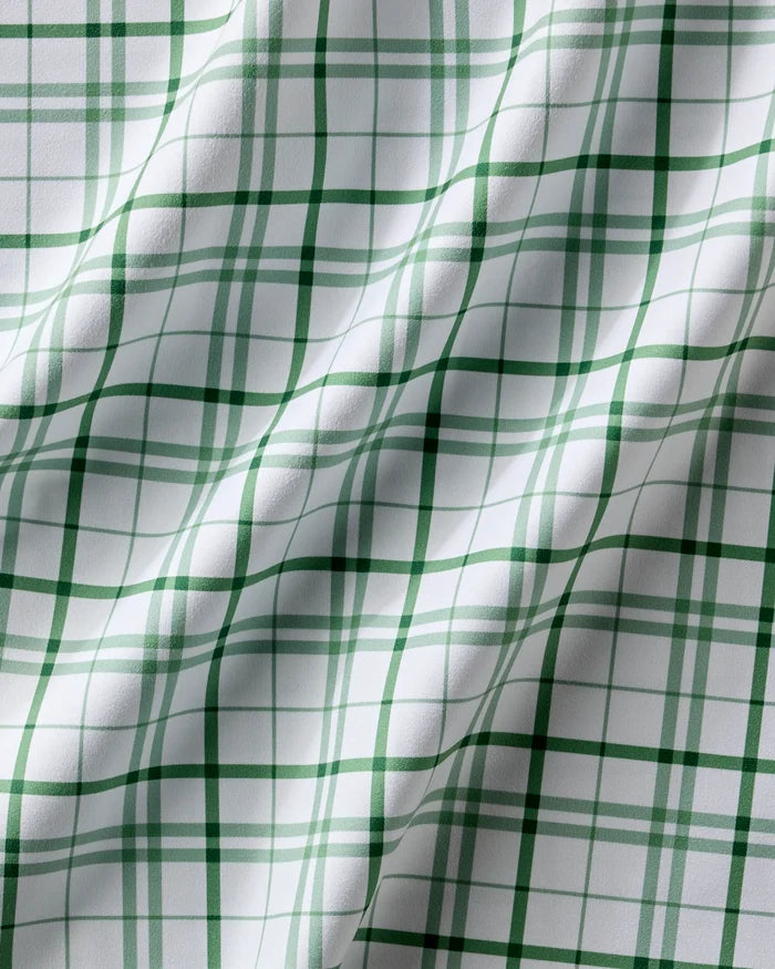 A close-up of Spring Picnic Plaid by Hufton Studio shows white fabric with a green plaid grid, soft folds, and shadows—these reusable table napkins are an eco-friendly choice for any dinner napkin set.