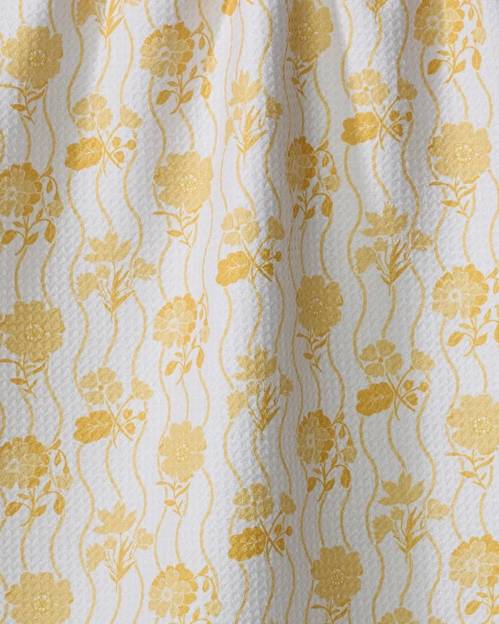 The Danelys Sidron "Spring Wave" tea towel features yellow floral and wavy line patterns on textured white fabric, adding a vintage decorative touch while providing ultra-absorbency for your kitchen.