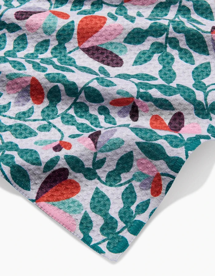 A close-up of the Claire Iglesias Spring Wavy Leaves Geoweave bar towel shows its colorful abstract floral and leaf pattern on white, highlighting the textured folds and eco-friendly, recycled materials.