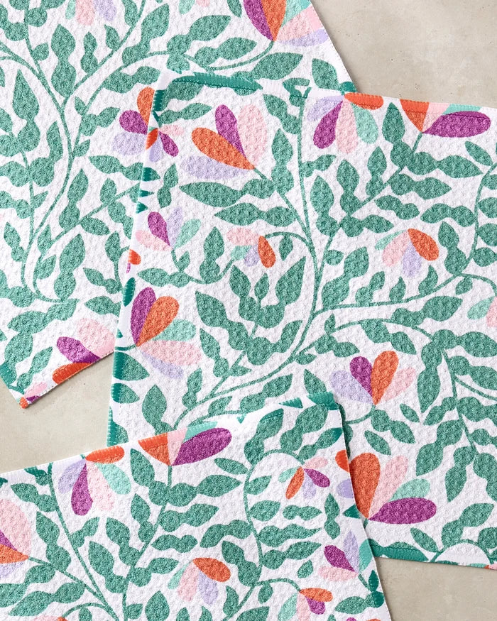 The Claire Iglesias Spring Wavy Leaves Dishcloth Set includes four super-absorbent cloths made from recycled materials, each adorned with a pattern of green leaves and vibrant floral blooms.
