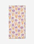 The Spring napkin by Kayla Ann is a rectangular Geoweave cloth featuring orange stems and leaves with purple flowers on a white background.
