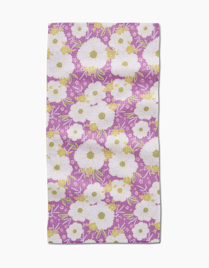 The Ashley Celena Springtime Floral Rectangular Bar Towel features white and yellow flowers with green leaves on purple Geoweave fabric, creating a vibrant, decorative accent for any space.