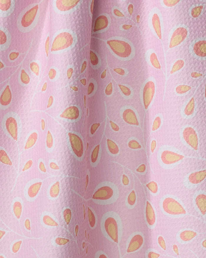 Close-up of the "Springtime Wonders" tea towel by Blissful Flamingo, featuring a textured pink surface and repeating white, yellow, and orange teardrop patterns. Made from recycled materials for an eco-friendly look.