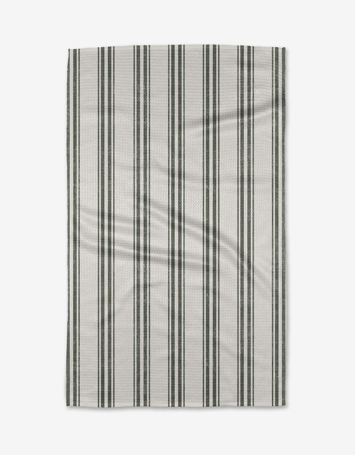 The Becki Owens Spruce tea towel is rectangular, white, and eco-friendly, with evenly spaced vertical dark green and light gray stripes—perfect for everyday kitchen use. Shown flat on a plain white background.