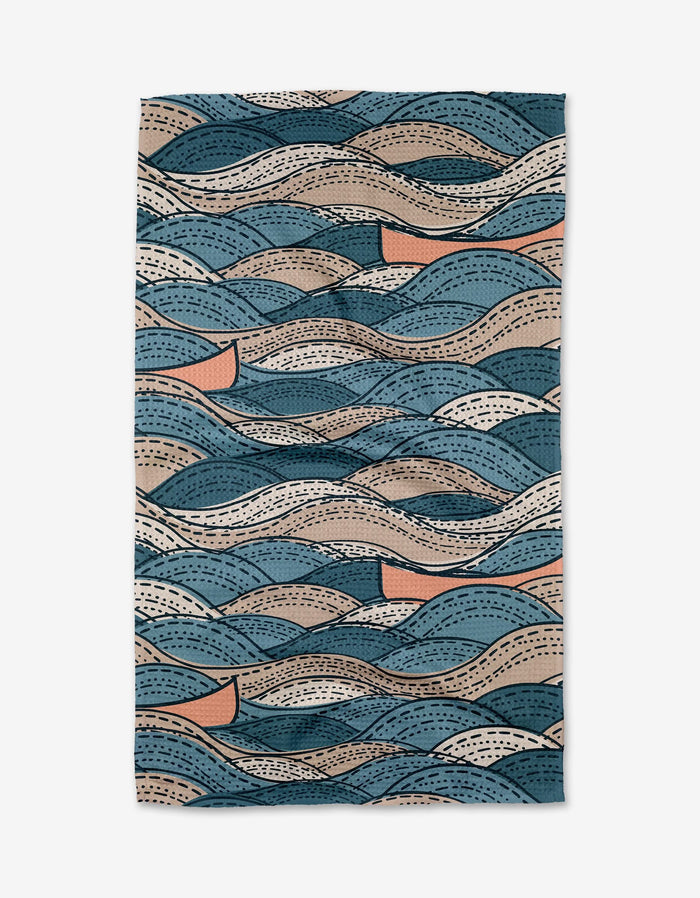 The Squall tea towel by Twig + Spark features an abstract wave pattern in blue, beige, brown, and peach with lines and dots for added texture. Made from ultra-absorbent Geoweave fabric.