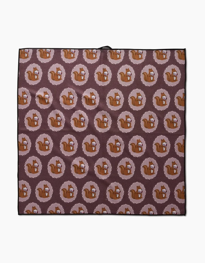 The Megan Roy Squirrels Brown mat is an eco-friendly, rectangular dog towel with a repeating pattern of brown squirrels in pink rings on a dark background. Highly absorbent and perfect for your furry friend.