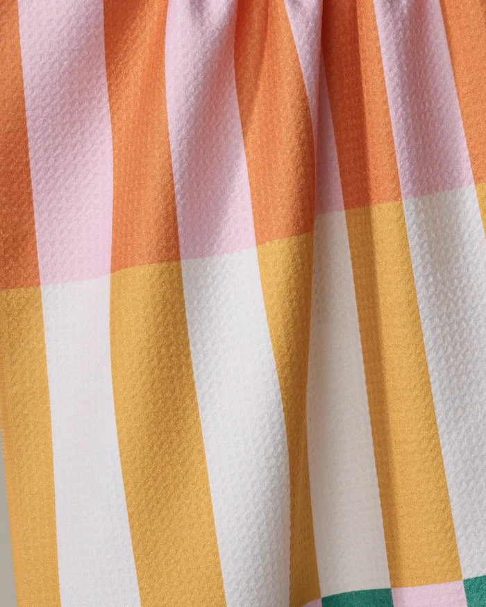 A close-up of Megan Roy's Stacked Stripes recycled kitchen towel, featuring a softly gathered top and a textured surface with vertical orange, pink, yellow, white, and green stripes in a bold geometric pattern.