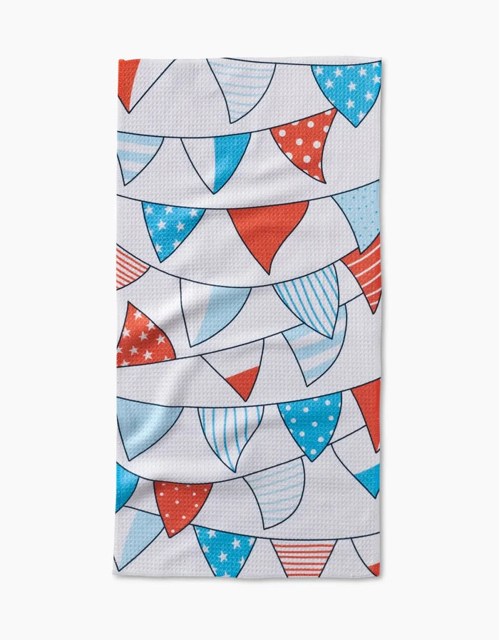 The Sara Mari Stars Stripes And Dots Bar Towel is rectangular and made with Geoweave™ fabric, featuring red, white, and blue pennant banners with stars, stripes, and polka dots on a crisp white background.