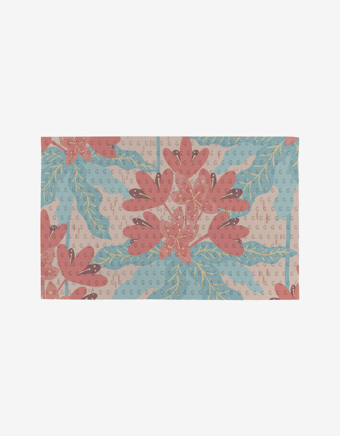 The State Flowers rug by Julianne Haness is a rectangular, eco-friendly piece featuring large red-pink flowers, blue leaves, and green stems on a light beige background with a subtle repeating G motif.