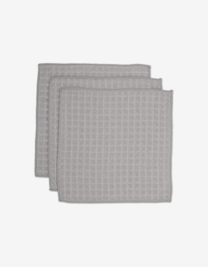 Three light gray GEOMETRY Stone Waffle Washcloths with a waffle texture are stacked slightly offset on a plain white background.