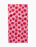 The Strawberry Fields Bar Towel by Charlie Rowan Designs, made from Geoweave fabric, features a pink background with a repeating red strawberry and green stem pattern, shown here against a white backdrop.