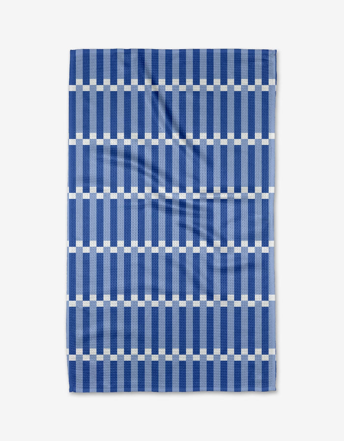 The Buy Guides Stripe Block - Blues is a kitchen tea towel made from recycled materials, featuring a geometric grid of dark blue stripes and white lines. The towel is shown flat with a few visible creases.