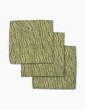 Three Stripe Funk Grounds Green placemats by Geometry, made from recycled materials, display wavy beige zebra-like stripes on green and are stacked slightly offset on a white background.
