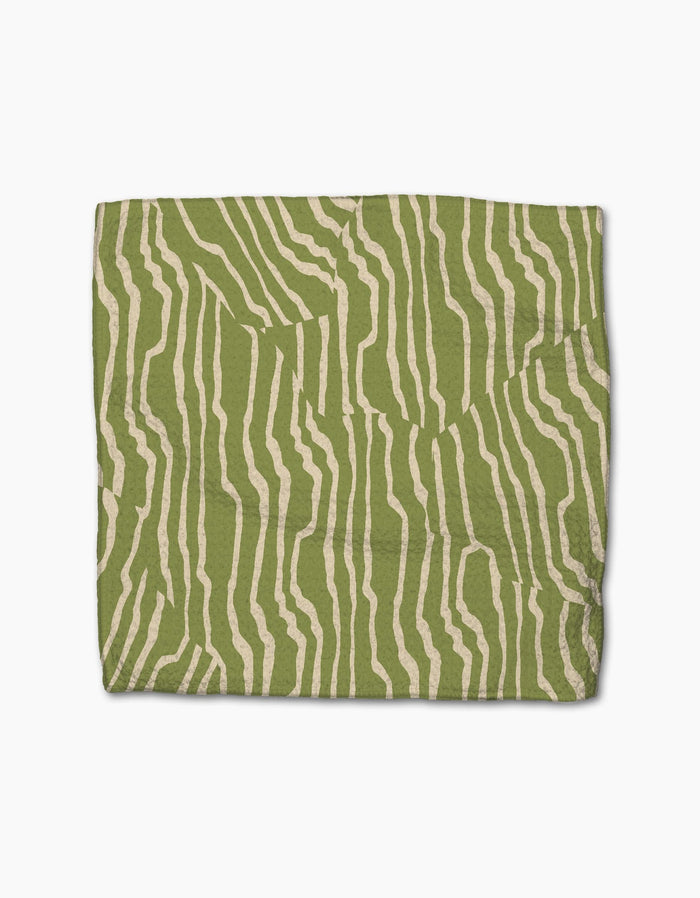 The Geometry Stripe Funk Grounds Green blanket is a rectangular, eco-friendly throw made from recycled materials, featuring an abstract cream wavy stripe pattern on a green backdrop.