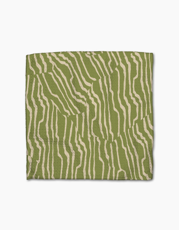 Geometry’s Stripe Funk Grounds Green quilt, crafted from recycled materials, features abstract cream wavy stripes on green, resembling zebra stripes. Displayed against a white background.
