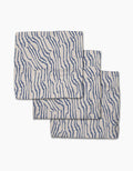 Three folded Stripe Funk Grounds napkins by Geometry, made from recycled materials, feature an abstract wavy blue line pattern and are stacked with slight overlap on a white background.